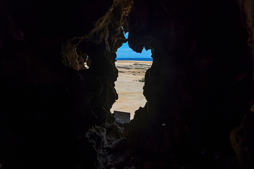 View of Quadirikiri Caves on Aruba Island in Arikok National Park with exterior opening in wall and view of Caribbean Sea.