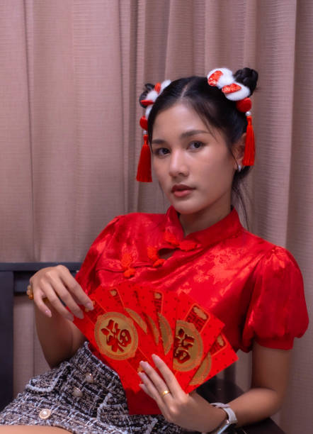 istock A beautiful woman with a sharp face wore a cheongsam. He was holding a red envelope and sitting on a chair. Envelopes are distributed at the festival. 2000208367