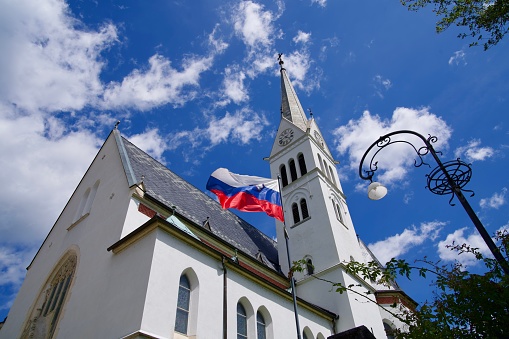 Scenic view of white St. Martin's Parish Church at lakeshore of Lake Bled on a cloudy summer day. Photo taken August 8th, 2023, Bled, Slovenia.