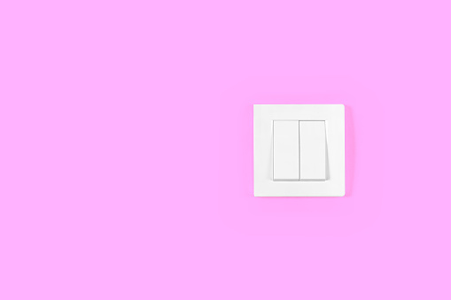 Light switch on pink wall. Electricity and light symbol.