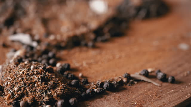 Mixture of Peppercorns on Wooden Spatula on Rotating Background of Dried Spices