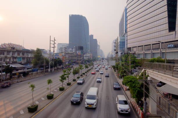 Bangkok, Thailand - Jan. 31, 2024: Traffic jam where motorcycles and cars navigate through significant haze of PM 2.5 air pollution, reflecting environmental and health concerns in urban settings.