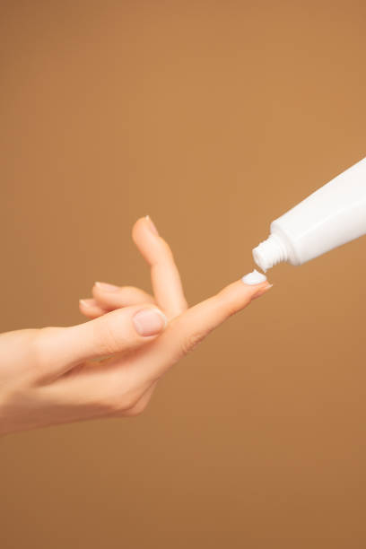 istock Closeup of model with hand pressed cream from white tube without label 2000213407