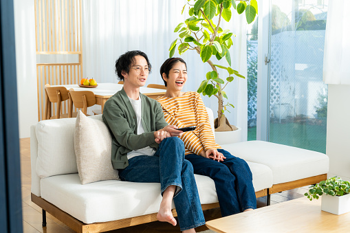 Young Japanese couple watching TV in the living room