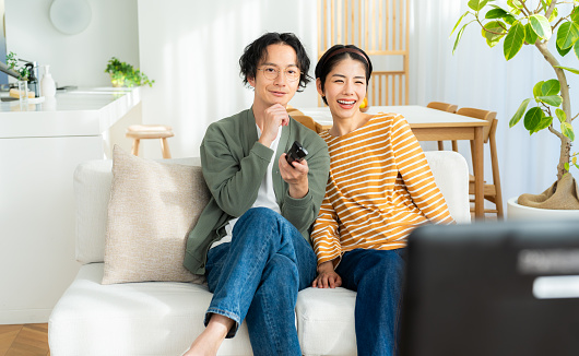 Young Japanese couple watching TV in the living room