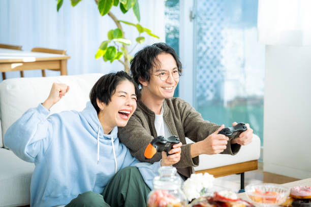 giovane coppia giapponese che gioca in salotto - racing game foto e immagini stock