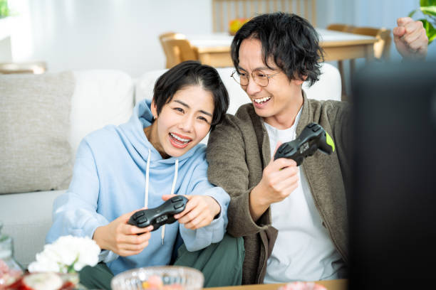 young japanese couple playing games in the living room - racing game imagens e fotografias de stock