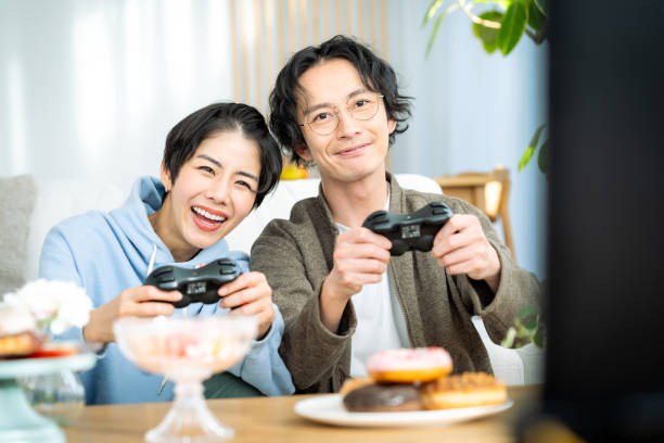 young japanese couple playing games in the living room - racing game imagens e fotografias de stock