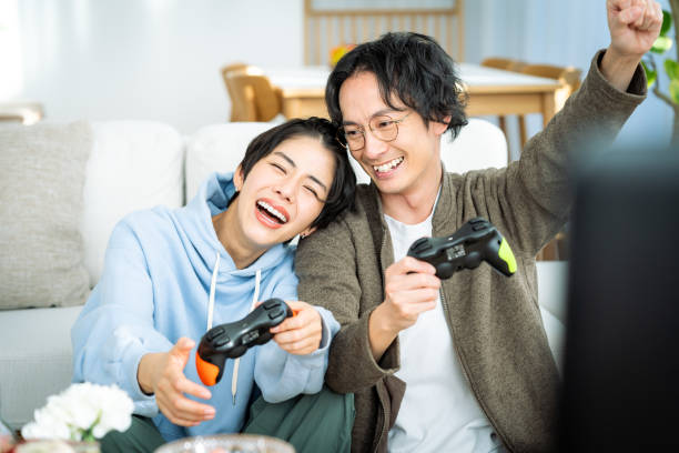 giovane coppia giapponese che gioca in salotto - racing game foto e immagini stock