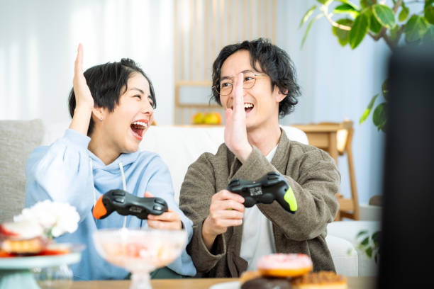 young japanese couple playing games in the living room - racing game imagens e fotografias de stock