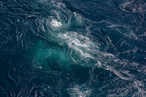 The deep blue of Saltstraumen's whirlpool waters is accentuated by the vigorous dance of tidal currents, offering a breathtaking texture and color palette