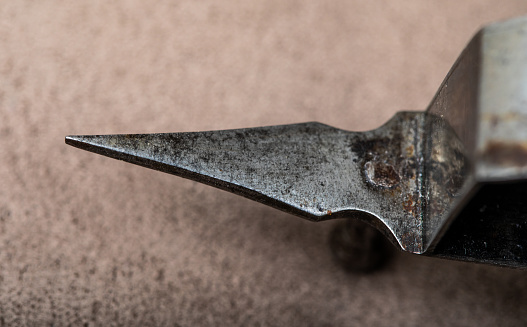 Studio shot of details of an antique metal candle snuffer and wick trimmer tool showing wear from use over time.