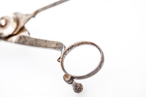 Studio shot of details of an antique metal candle snuffer and wick trimmer tool showing wear from use over time.