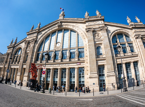 Paris, France - May 20, 2018: ultra wide-angle view of French street with iconic tall building of Gare du Nord with large group of pedestrians commuting