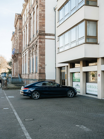 Strasbourg, France - Feb 23, 2019: Luxury Mercedes-Benz Coupe car parked in the center of Strasbourg Place Broglie with City-Hall building in background