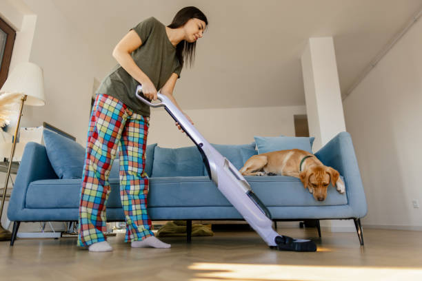 istock Young woman vacuuming living room 2000289438