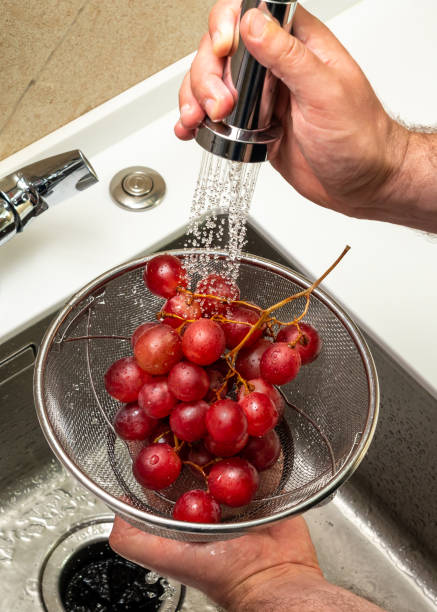 Washing red grapes in a strainer under running water