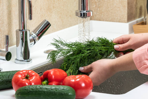 istock Women's hands wash vegetables in the kitchen in the sink 2000320843