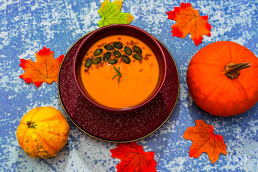 Diet pumpkin soup in a brown bowl on a blue background