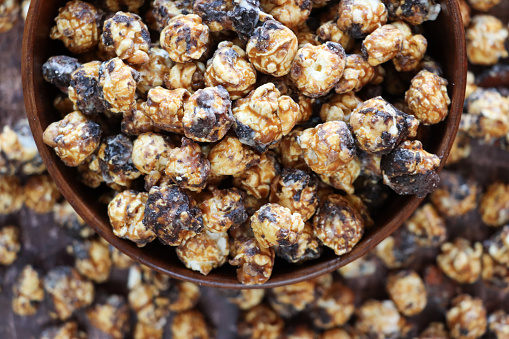 Stock photo showing close-up, elevated view of round tin of Belgian, dark chocolate covered popcorn.