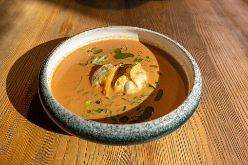 Nepalese Momo Jhol Achar Dumpling Soup, Fried Gyoza Broth, Spicy Tomato Momo Seasoned Soup in Exquisite Serving Restaurant Bowl in Sunlight Closeup