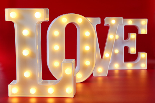 Stock photo showing an illuminated love sign, with the word 'LOVE' being spelt out by individual letters lit by bright white light bulbs.