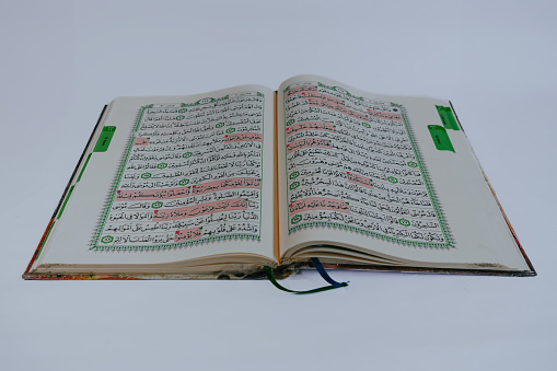 The holy Qur'an.\nTop view, open page of holy book al qur'an on white background.