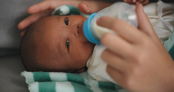 Close up image, Selective focus face of Newborn wake up and Young asian mother feeding her baby from a bottle