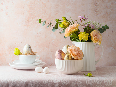 Easter holiday celebration with flowers bouquet and Easter eggs decoration on table over bright  background