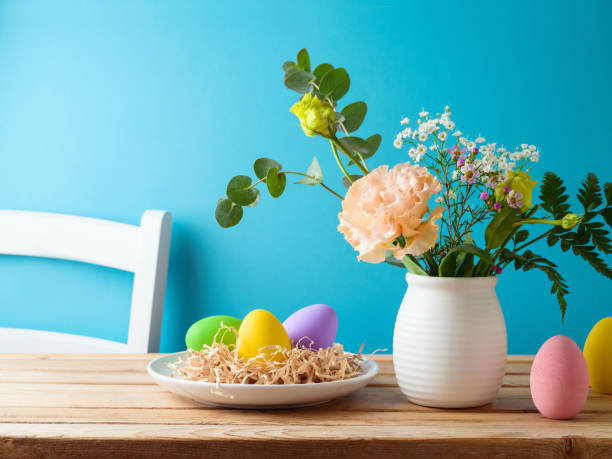 istock Easter holiday egg decoration and  flowers bouquet on wooden table over blue  background 2000350738