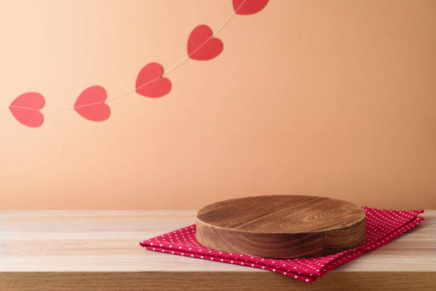 istock Empty wooden log podium on  table with tablecloth and heart shape garland over peach color background.  Valentine's day mock up for design and product display 2000350751