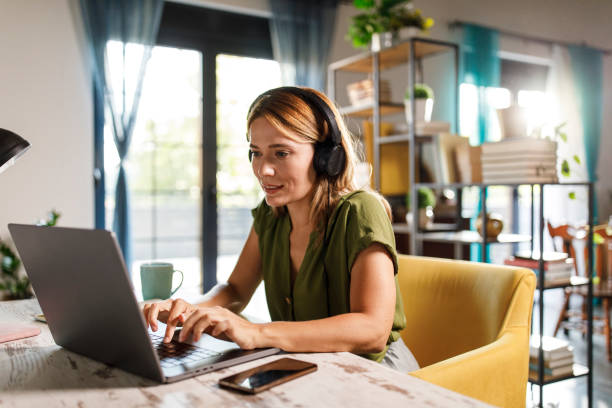 istock Woman listening to music while working at her desk 2000359411