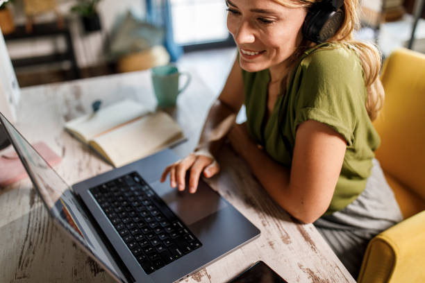 istock Woman listening to music while working at her desk 2000359441