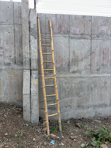 Wooden ladder against concrete wall closeup