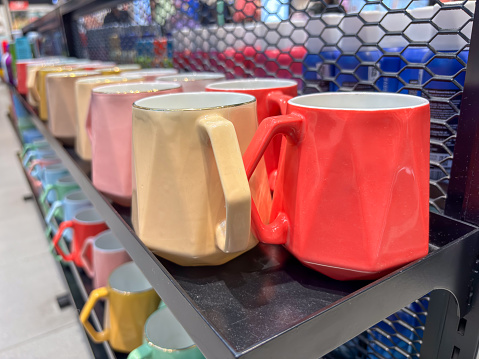Closeup of ceramic cups of different colors and sizes close-up. Multi-colored cups covered with special glazed.