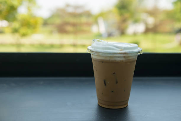 Ice cappuccino coffee on table with spring garden view of outdoor cafe and restaurant.