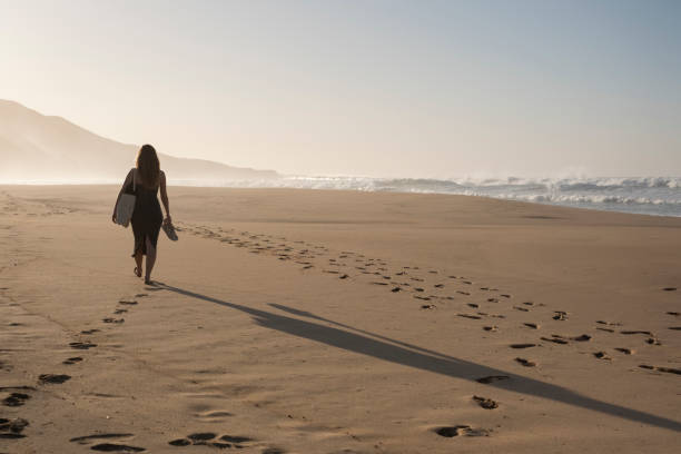 istock Woman from behind walking towards the horizon on the beach 2000403433