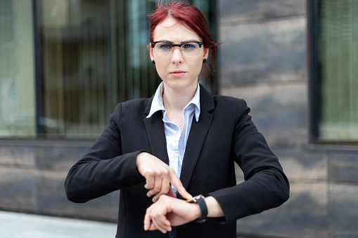 Angry businesswoman pointing at ther watch because you're late