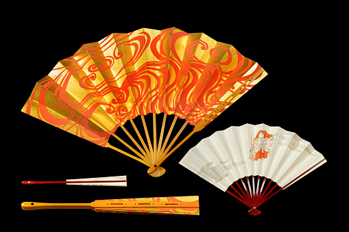 Japanese traditional hand fans from paper and bamboo with gold and red ornament, isolated on black.