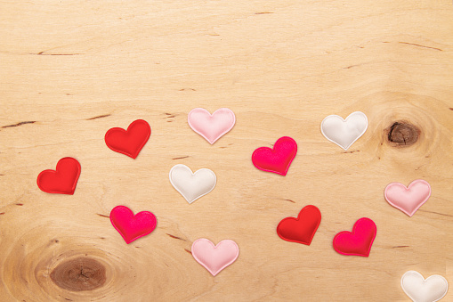 A lot of small hearts on wooden background with copy space. Greeting card with Enchanting love notes on textured wood.