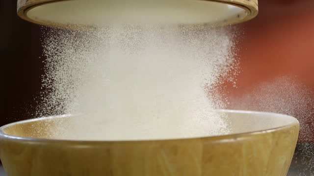Person sifting white flour for baking. Wooden sieve