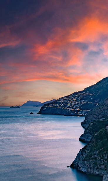 amalfiküste, italien. blick über praiano an der amalfiküste bei sonnenuntergang. straßen- und hausbeleuchtung in der abenddämmerung. in der ferne die insel capri am horizont. straße an der amalfiküste. meereslandschaft. vertikales bild. - vertical horizon over land beauty in nature beautiful stock-fotos und bilder