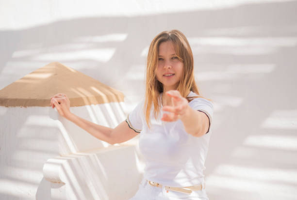 A beautiful woman gazes directly at the camera, her captivating eyes expressing both warmth and connection. With an inviting gesture, she extends her hand.