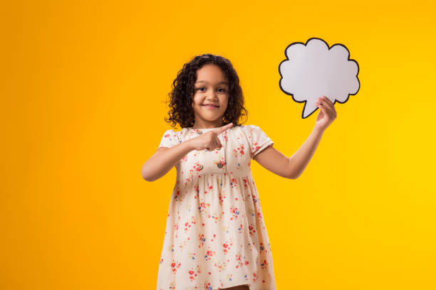 istock Smiling kid girl pointing finger at cloud bubble card. Dreaming concept 2000434865