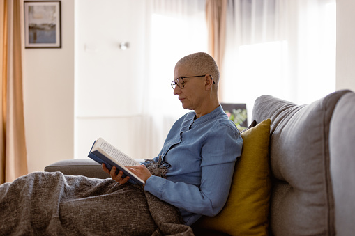 Living with cancer. Woman reading book