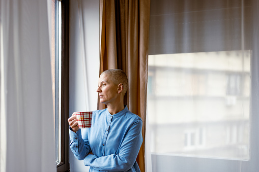 Living with cancer. Sad woman beside the window