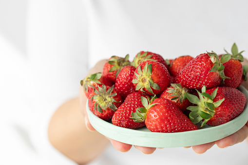 A woman holding is strawberries.