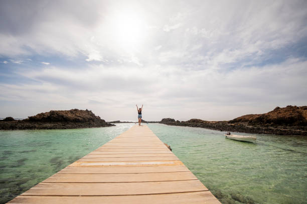 istock Ocean Bliss: Woman with Arms Raised on a Wooden Boardwalk 2000450286
