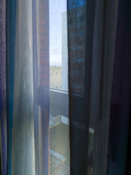istock Urban Perspectives: View through the window with curtain to the blue sky and building. 2000450809