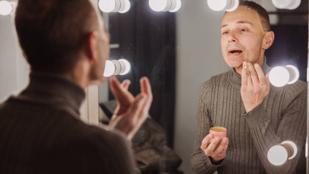 istock Metrosexual mid-adult man applying an face cream while observing himself in the mirror 2000454481